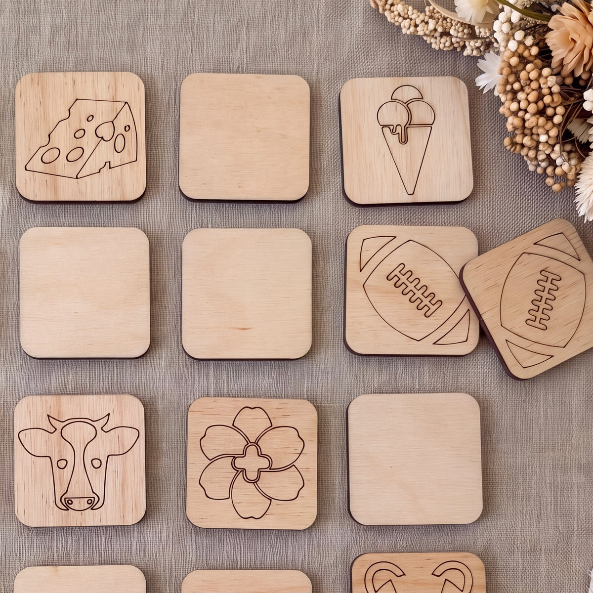 a collection of wooden coasters or tiles with various designs, including a cow, a football, and other abstract shapes.