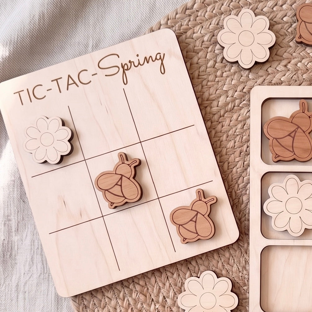 A wooden tic-tac game board labeled "TIC-TAC-Spring" with wooden tic-tac pieces featuring a bee and a flower design.