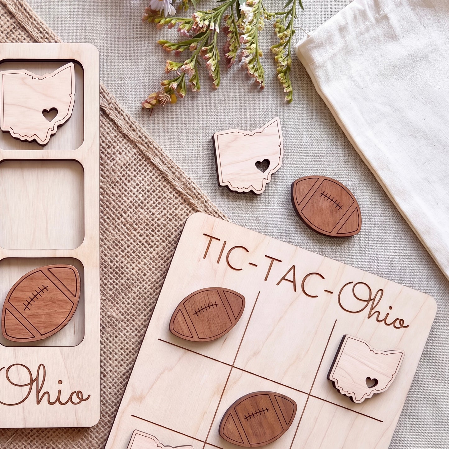 a wooden tic-tac game with the word "Ohio" written on it, along with several wooden pieces shaped like Ohio state symbols, such as a heart and a football.