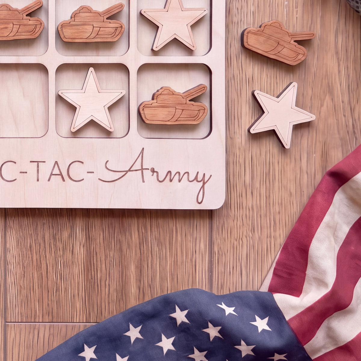 a wooden game board with a tic-tac game set up on a wooden surface, along with a wooden star and a wooden tank. There is also an American flag in the background.