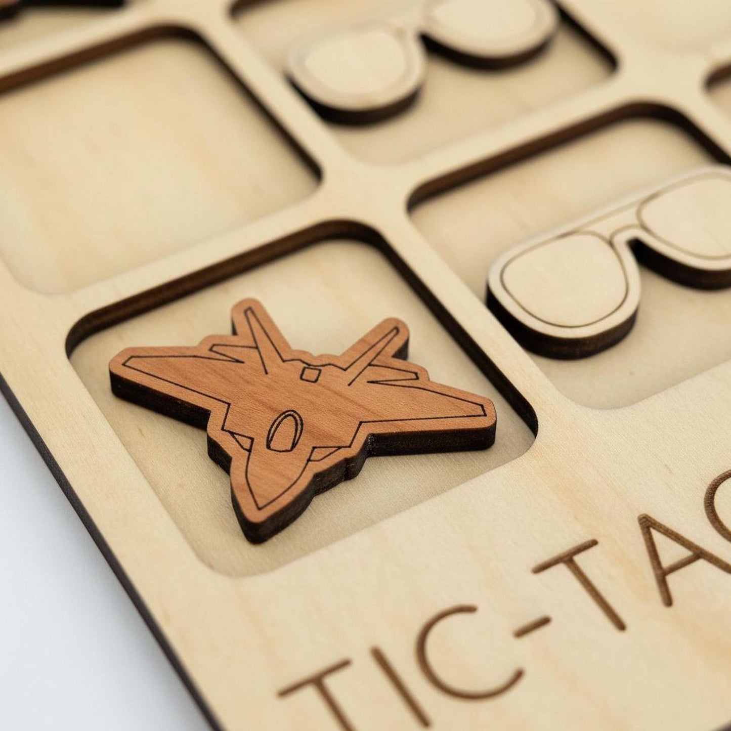 A wooden tic-tac board with a small wooden airplane cutout in the center.