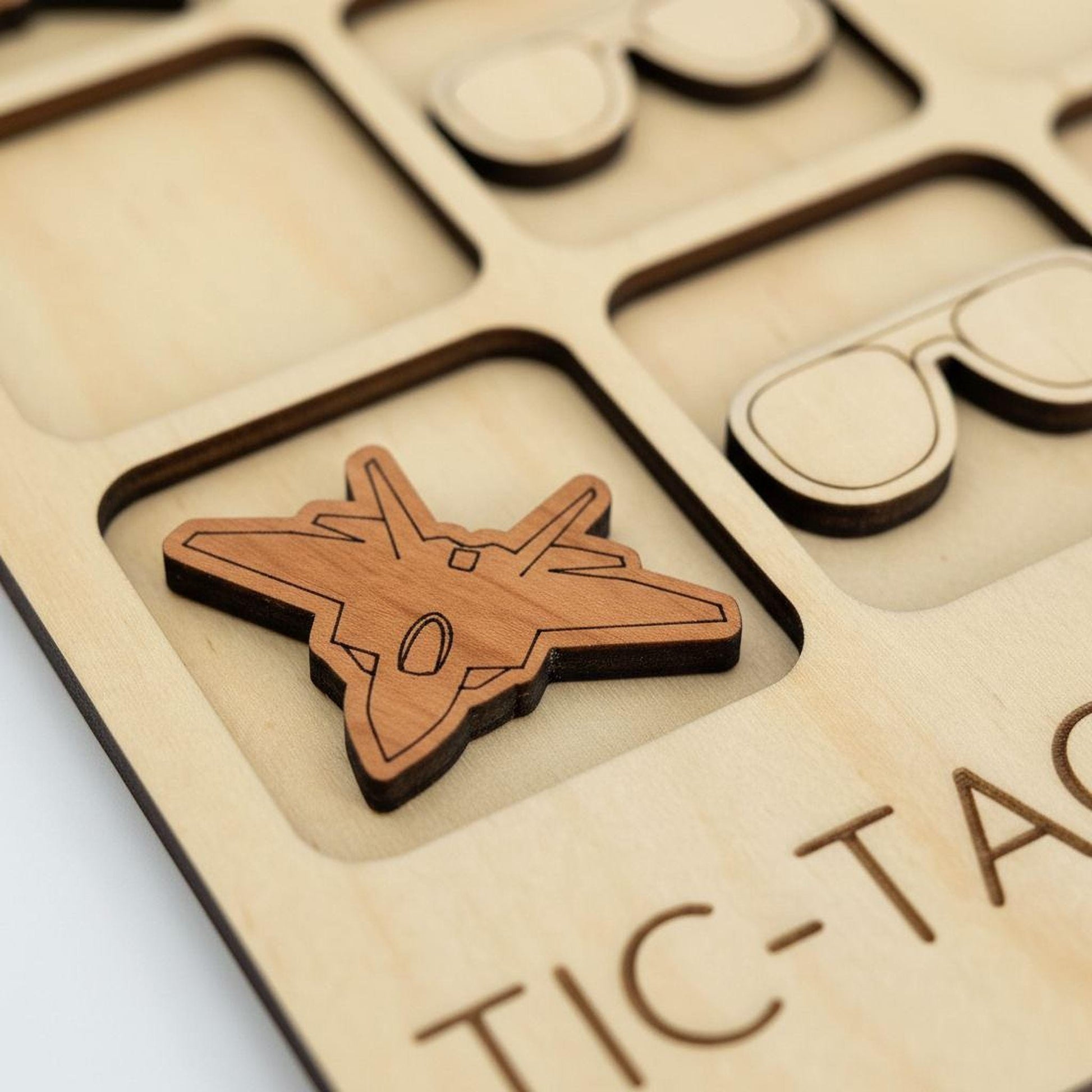 A wooden tic-tac board with a small wooden airplane cutout in the center.