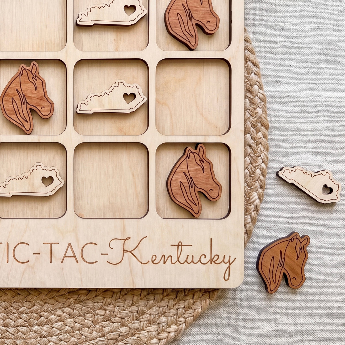 A wooden tic-tac game board with wooden horse head tiles and the word "Kentucky" written on it.