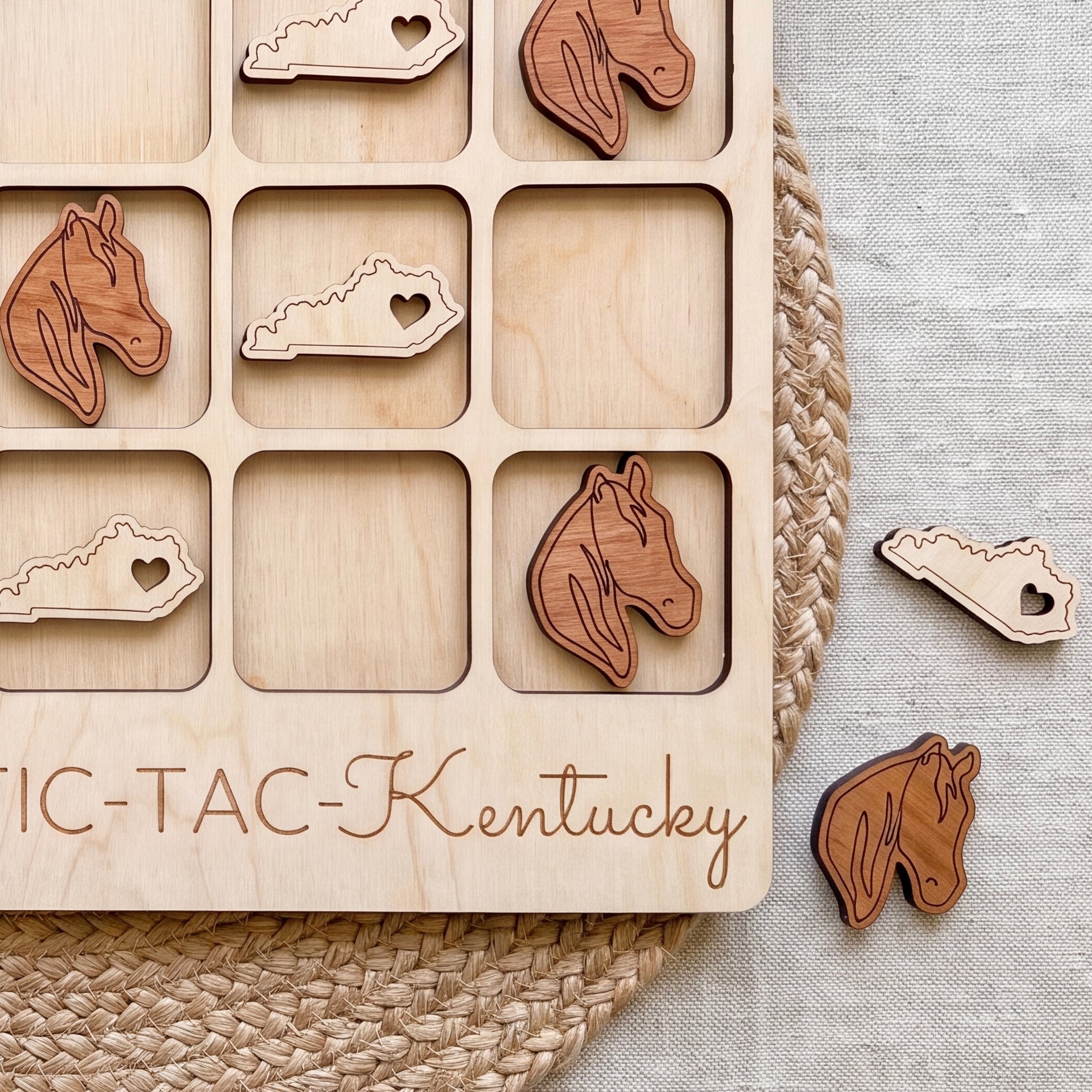 A wooden tic-tac game board with wooden horse head tiles and the word "Kentucky" written on it.