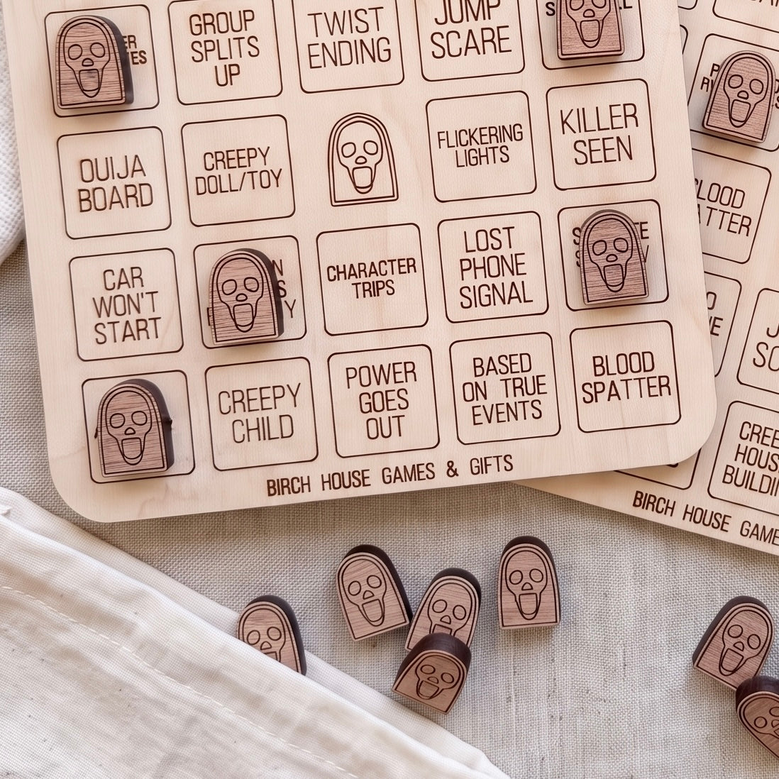 a collection of wooden game pieces with spooky faces, likely intended for a game or activity related to the theme of the spooky house.