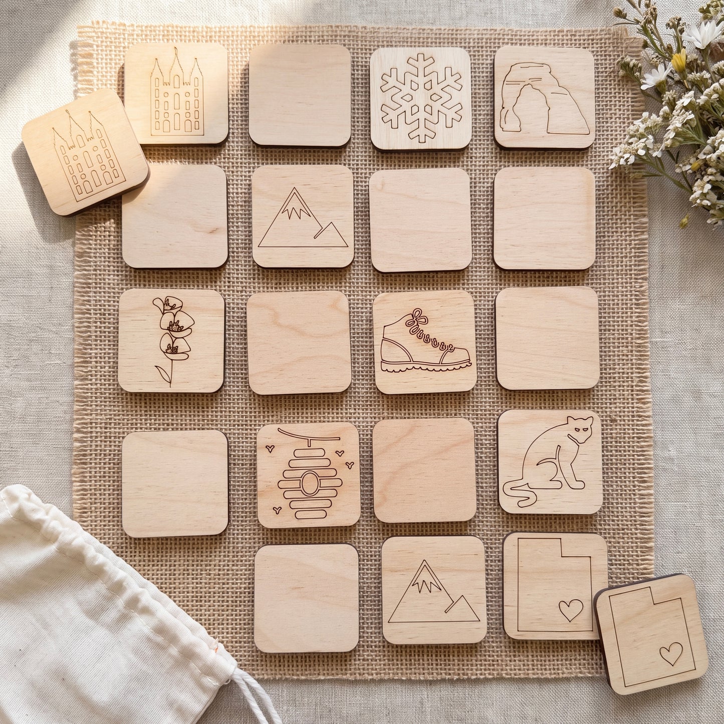 a collection of wooden coasters or game pieces with various designs and symbols printed on them, arranged on a burlap cloth or similar textured surface.