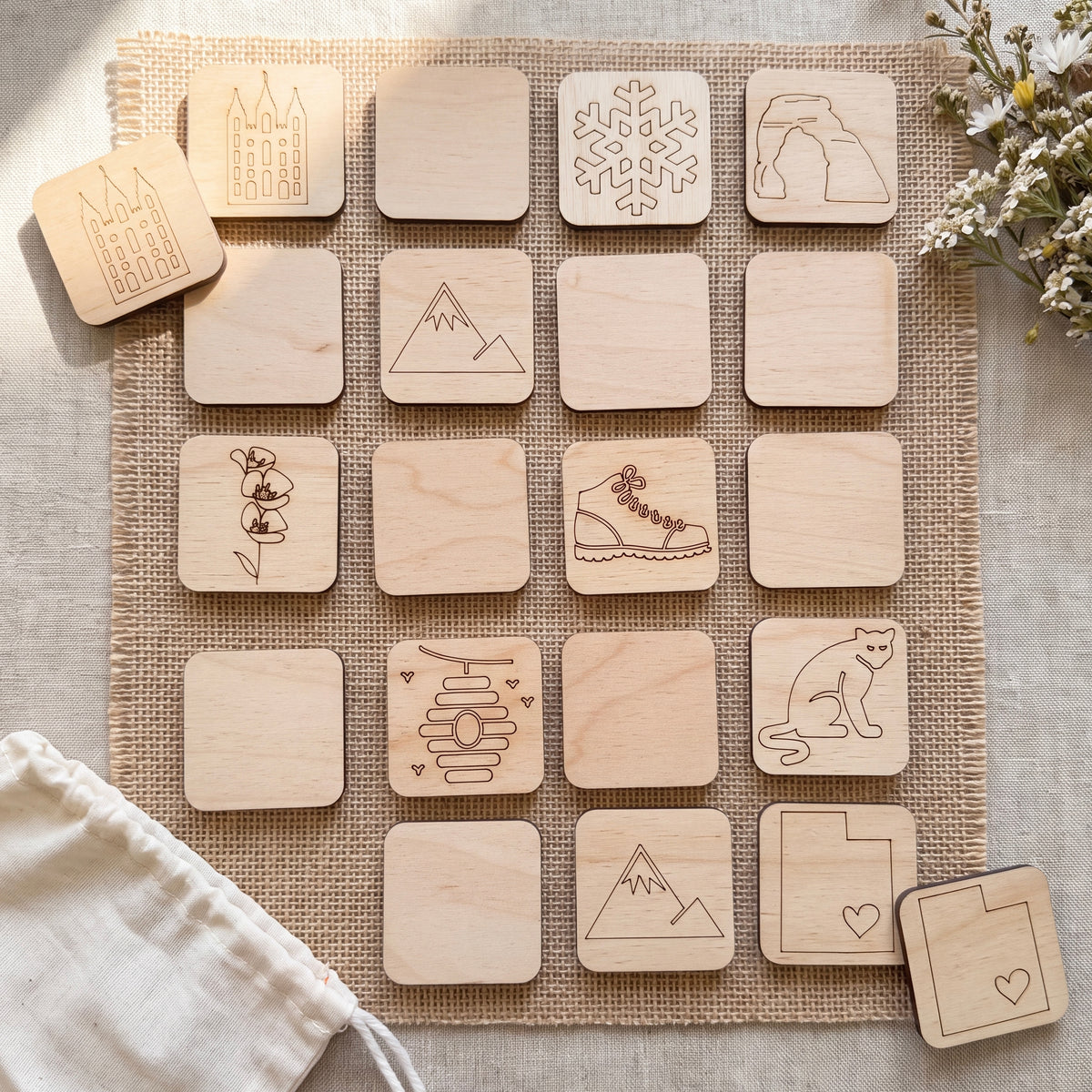 a collection of wooden coasters or game pieces with various designs and symbols printed on them, arranged on a burlap cloth or similar textured surface.