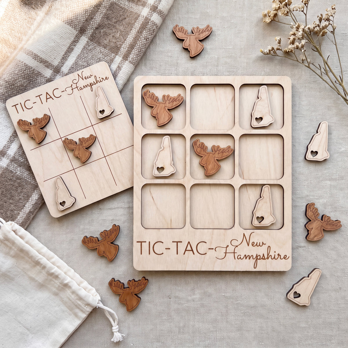 a wooden tic-tac game with a New Hampshire theme, including a wooden tic-tac board and wooden tic-tac pieces shaped like moose heads.