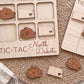 a wooden tic-tac game board with the word "North Dakota" written on it, along with several wooden pieces shaped like flowers.