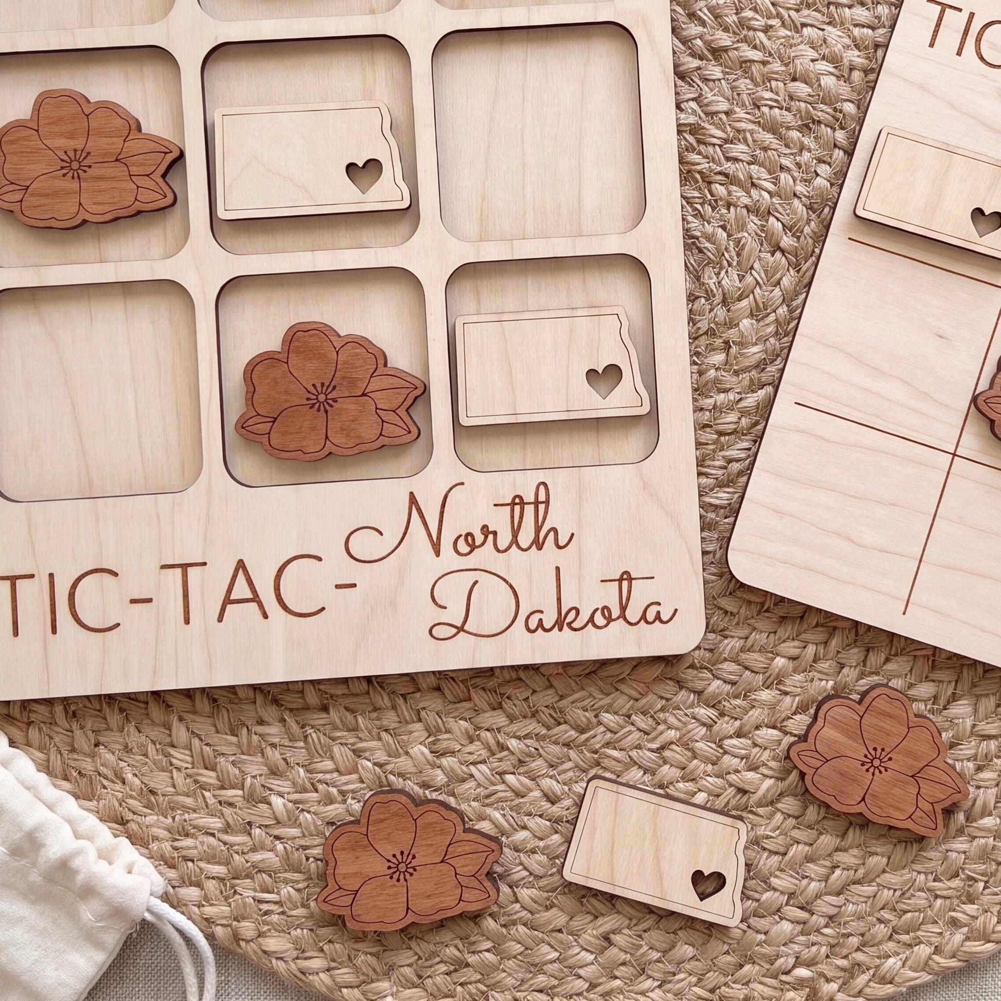 a wooden tic-tac game board with the word "North Dakota" written on it, along with several wooden pieces shaped like flowers.