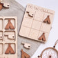 a wooden tic-tac game board with wooden tiki-style pieces and a dreamcatcher.