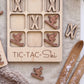 A wooden tic-tac game with a ski theme, featuring wooden pieces shaped like skiers and snowboards.