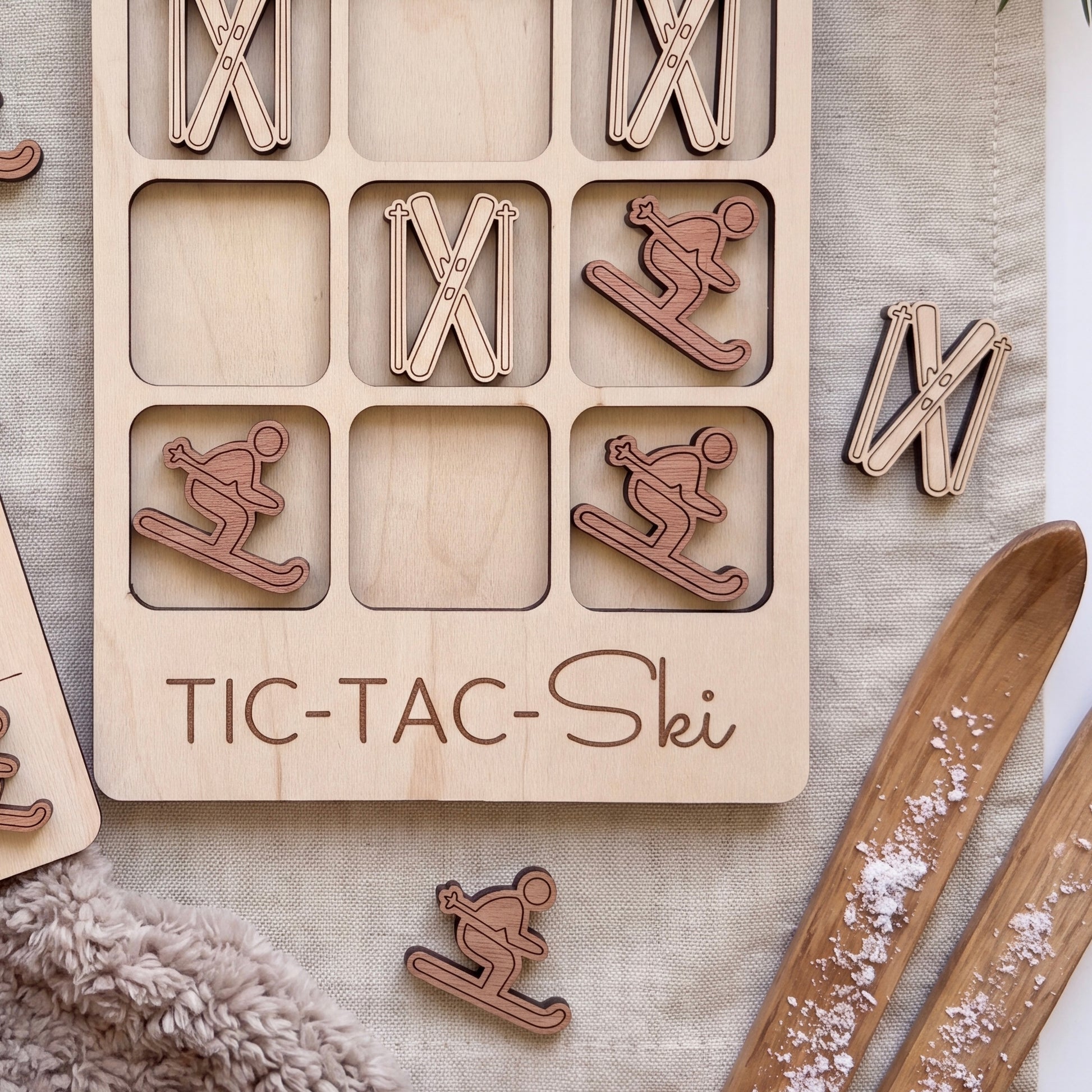 A wooden tic-tac game with a ski theme, featuring wooden pieces shaped like skiers and snowboards.