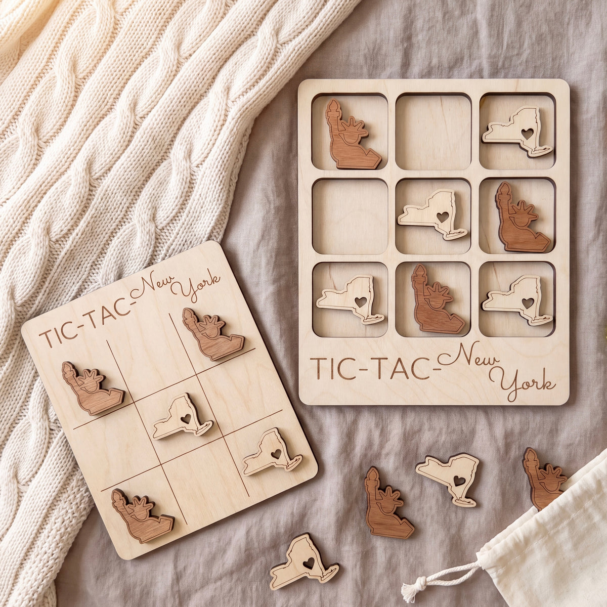 a wooden tic-tac game board and wooden tic-tac pieces, both labeled "TIC-TAC New York". The tic-tac pieces are arranged on the board, and there is a white cloth or blanket in the background.
