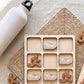 a wooden puzzle with a grid of nine squares, each containing a wooden shoe icon. A white water bottle is placed next to the puzzle, and there are additional wooden shapes scattered around the puzzle.