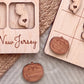 a wooden frame with a New Jersey state map and a wooden tic-tac game board with wooden tiles.