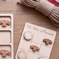 a wooden tic-tac game board with wooden pieces shaped like birds, and a coiled rope is also present on the wooden surface.