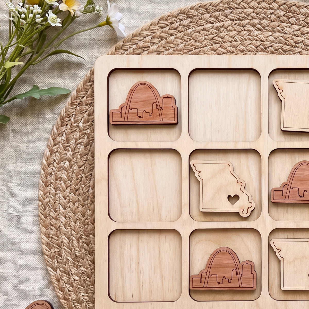 a wooden puzzle with nine pieces, each depicting a different state in the United States. The puzzle is placed on a woven placemat, and there are some flowers visible in the background.