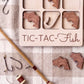 a wooden tic-tac game with fish-shaped tiles, a fishing rod, and some hooks, all arranged on a checkered cloth.