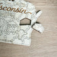 A wooden puzzle depicting the state of Wisconsin, with pieces shaped like a house, cow, and other state symbols.