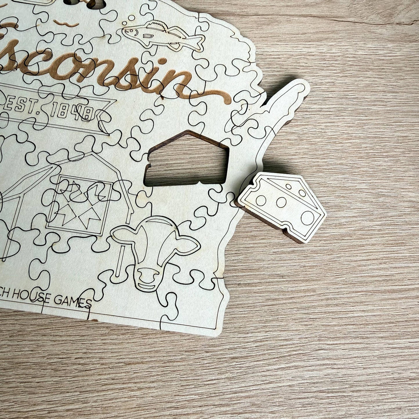 A wooden puzzle depicting the state of Wisconsin, with pieces shaped like a house, cow, and other state symbols.