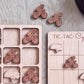 a wooden game board with a tic-tac game board and several wooden tic-tac pieces depicting bicycles and helmets.