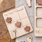 a wooden tic-tac game board with wooden pieces shaped like leaves and a wooden piece shaped like a state.