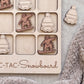 A wooden tic-tac-toe board with snowboard-themed tiles, featuring a snowboarder and snowboard icons.