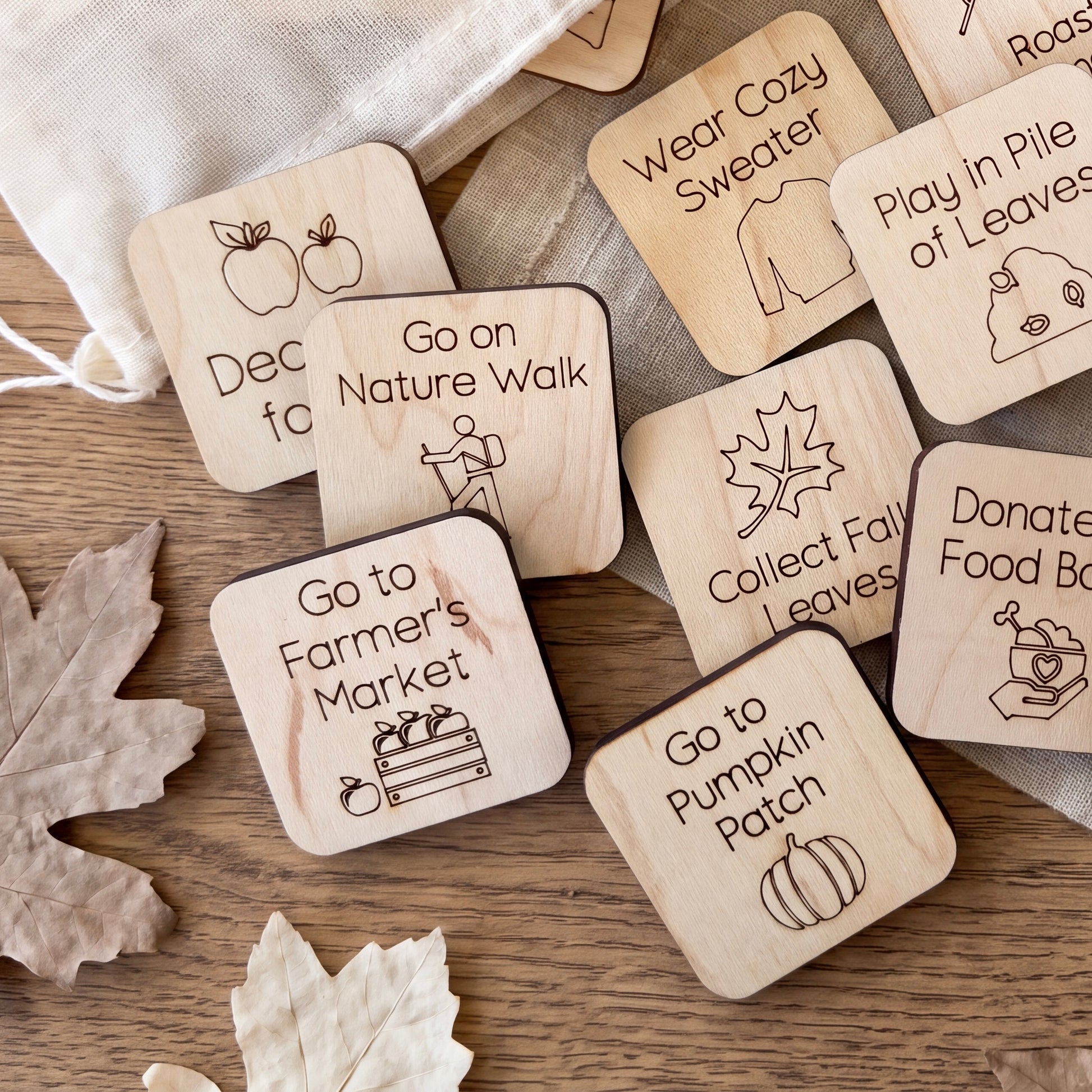 a collection of wooden stickers or labels with various fall-themed illustrations, such as apples, pumpkins, leaves, and a sweater.