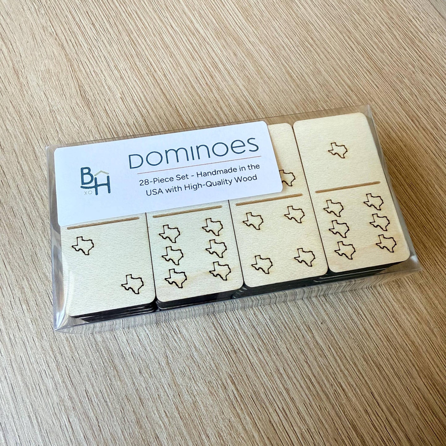 A package of wooden dominoes with a clear plastic cover, featuring a set of 28 dominoes with a design of Texas state icons.
