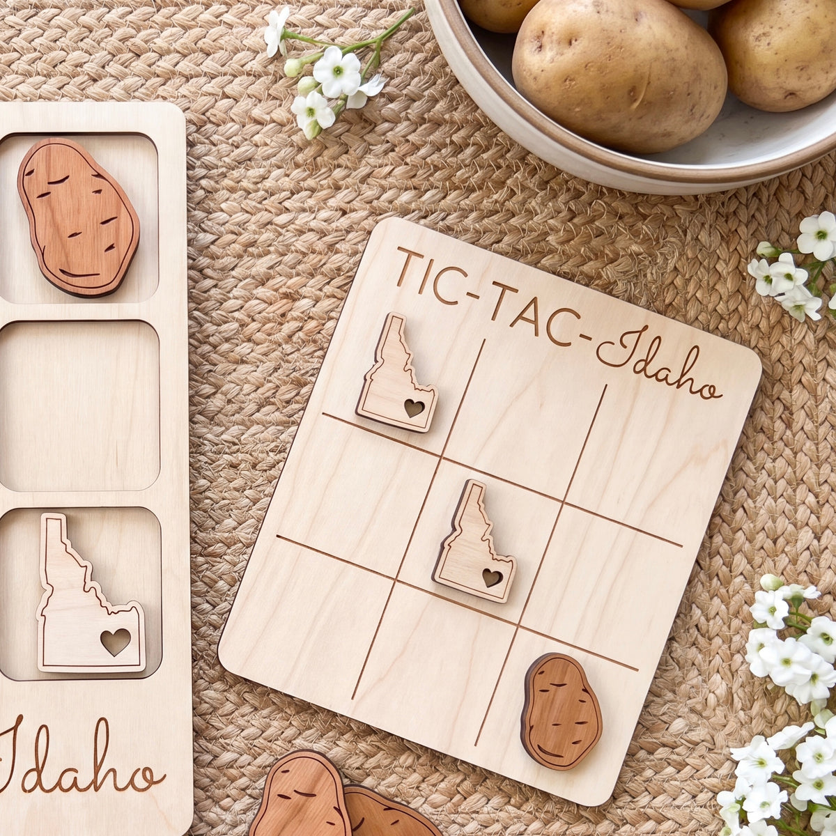 a wooden tic-tac game with Idaho state symbols on it, along with a bowl of potatoes and some flowers.