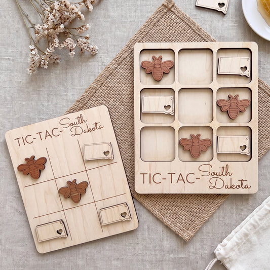 two wooden game boards, each with a set of wooden pieces shaped like bees, arranged on a beige cloth.