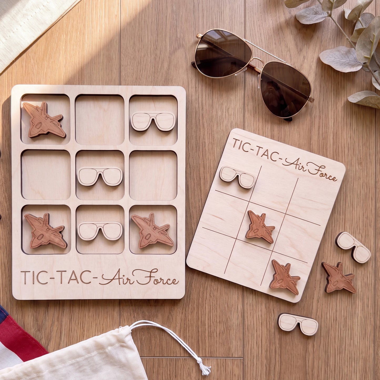 a wooden game board labeled "TIC-TAC-Air Force" and a pair of sunglasses, along with some additional sunglasses and a pair of sunglasses on a wooden surface.