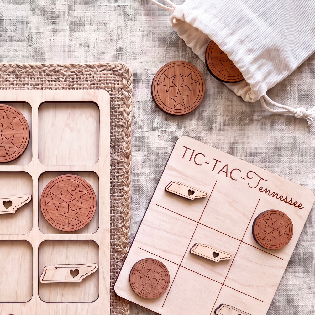 a wooden tic-tac game board with wooden pieces shaped like the state of Tennessee, and a white drawstring bag with a similar design.