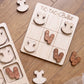 a wooden game board with a Tic-Tac ballet theme, along with several wooden pieces shaped like ballet shoes and tutus.