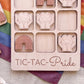 A wooden tic-tac game with the word "TIC-TAC-Pride" written on it, along with various heart-shaped and rainbow-shaped tiles.