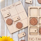 a wooden tic-tac game board with wooden pieces shaped like flowers, and a wooden frame with wooden pieces shaped like flowers.