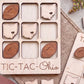A wooden tic-tac game board with the word "TIC-TAC-OHIO" printed on it, along with various wooden game pieces shaped like footballs and state maps.