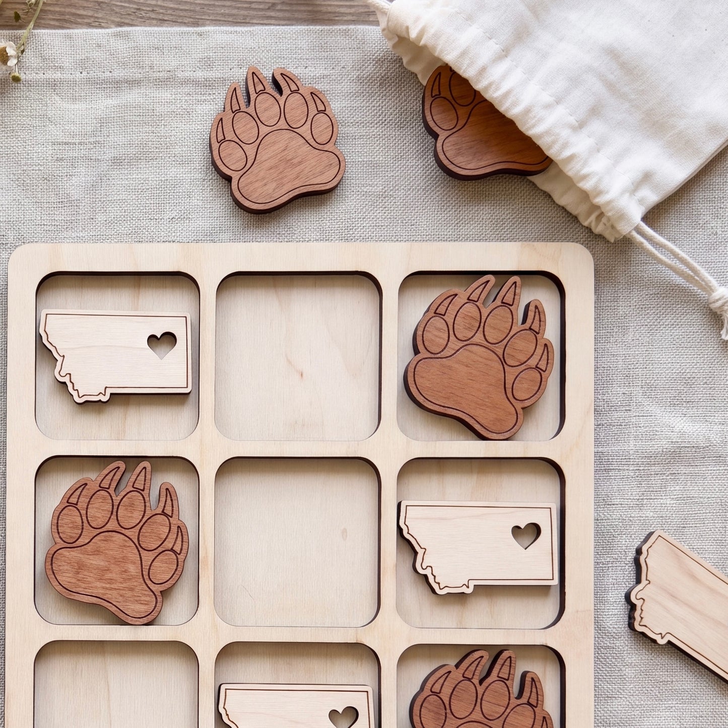 a wooden tic-tac game with wooden paw print cutouts, arranged in a grid-like pattern.