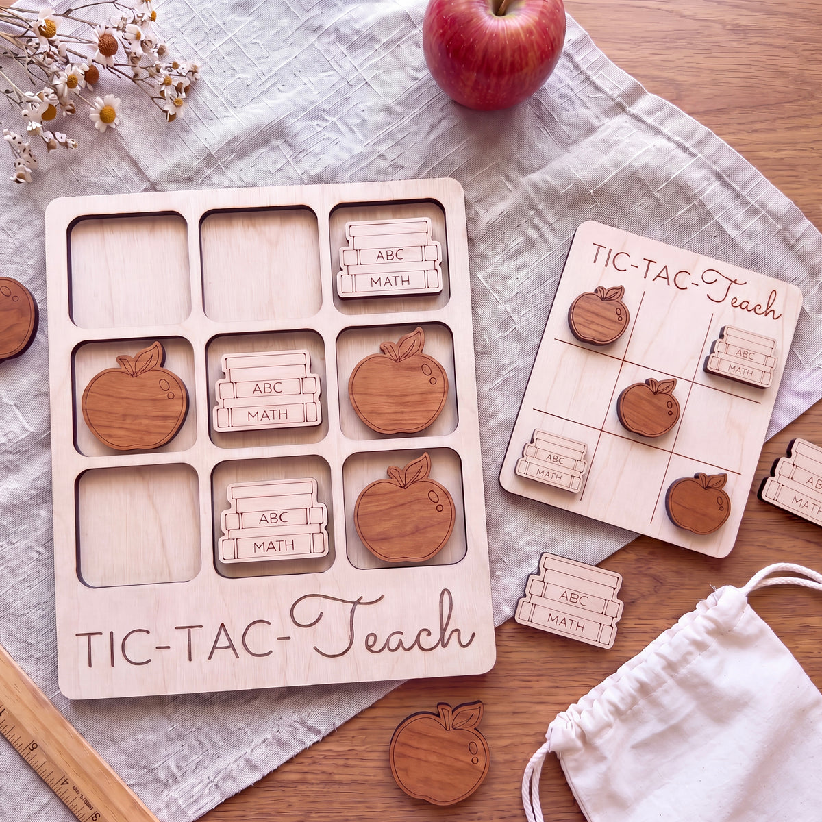 a wooden educational game board labeled "TIC-TAC-Teach" and various wooden shapes labeled with letters, such as "ABC", "MATH", and "ABC", suggesting it is a learning game for children.