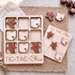 a wooden tic-tac-toe game with Ohio state shapes as game pieces, placed on a woven placemat.