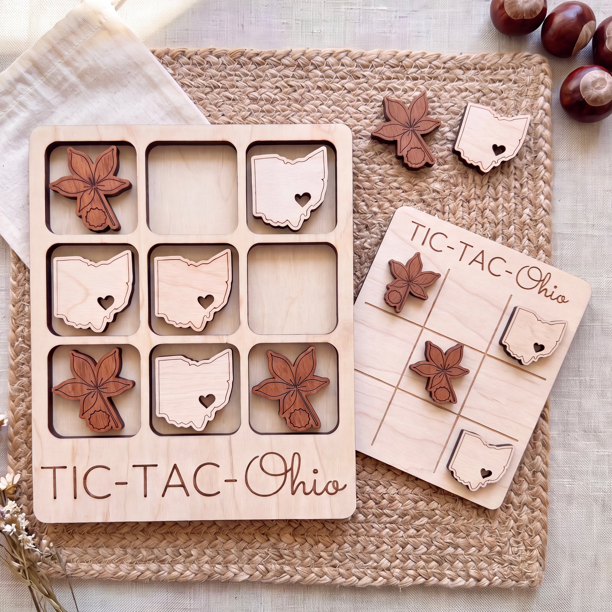 a wooden tic-tac-toe game with Ohio state shapes as game pieces, placed on a woven placemat.