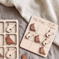 a wooden tic-tac game board with bird-shaped tiles, and a blanket with a patterned texture is visible in the background.