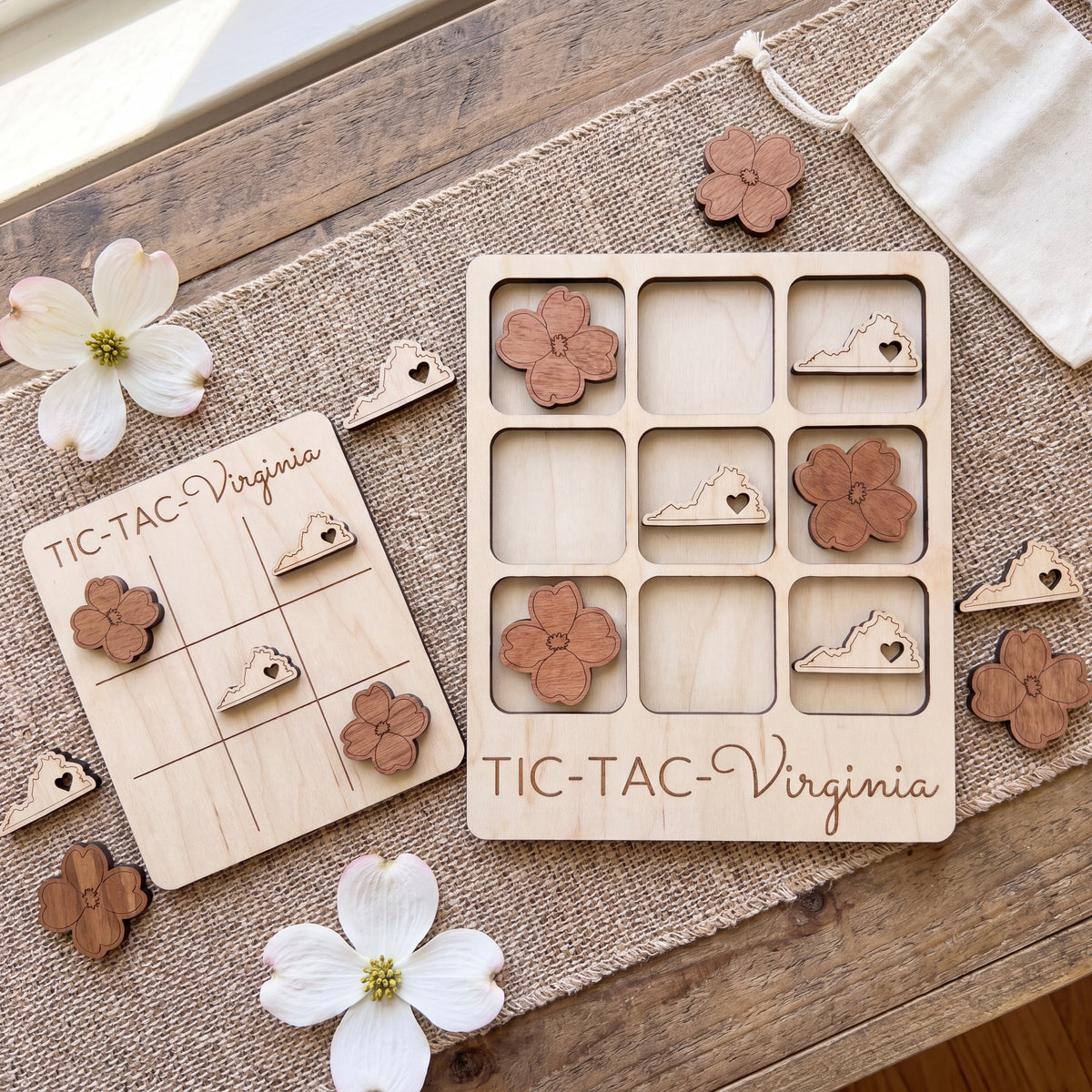 a wooden Tic-Tac game board and wooden pieces shaped like flowers, specifically from Virginia, placed on a wooden surface.