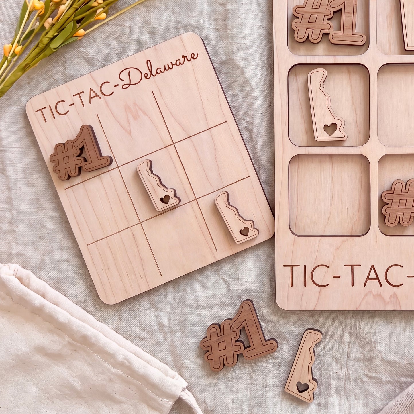 a wooden tic-tac game board with wooden pieces shaped like numbers and states, including Delaware, placed on a white cloth.