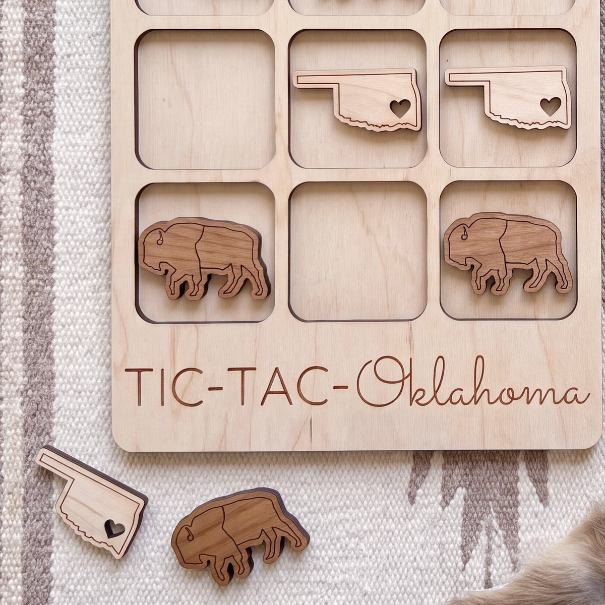 a wooden tic-tac game with the word "Oklahoma" written on it, along with several wooden pieces shaped like bison.