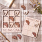 a wooden game board and a wooden puzzle with fish-shaped pieces, both placed on a checkered cloth.