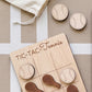 A wooden tic-tac game board with wooden tennis balls and wooden rackets, along with a white bag and a white stripe on the surface.