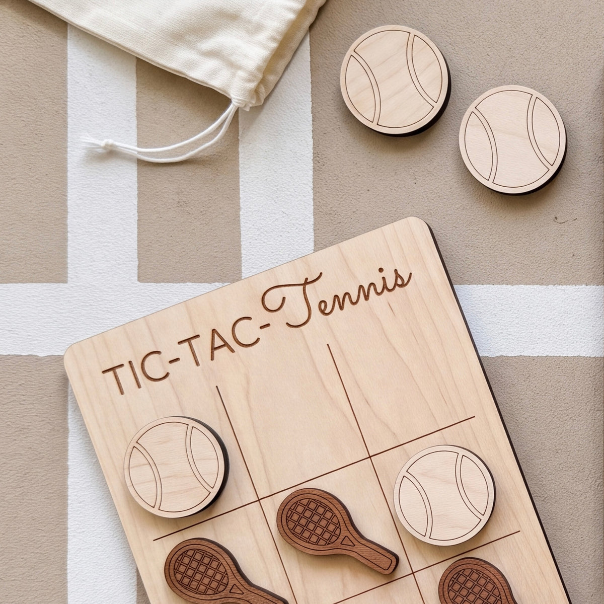 A wooden tic-tac game board with wooden tennis balls and wooden rackets, along with a white bag and a white stripe on the surface.