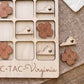 A wooden tic-tac board with wooden pieces shaped like flowers and the word "VIRGINIA" written on it.